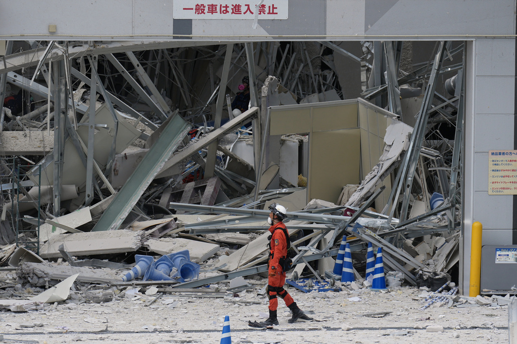 A rescue worker walks in front of AEON Mall, which was damaged by an explosion following an earthquake, is seen in Kashima, Kumamoto Prefecture, southern Japan, Wednesday, July 29, 2026. (AP Photo/Hiro Komae)
