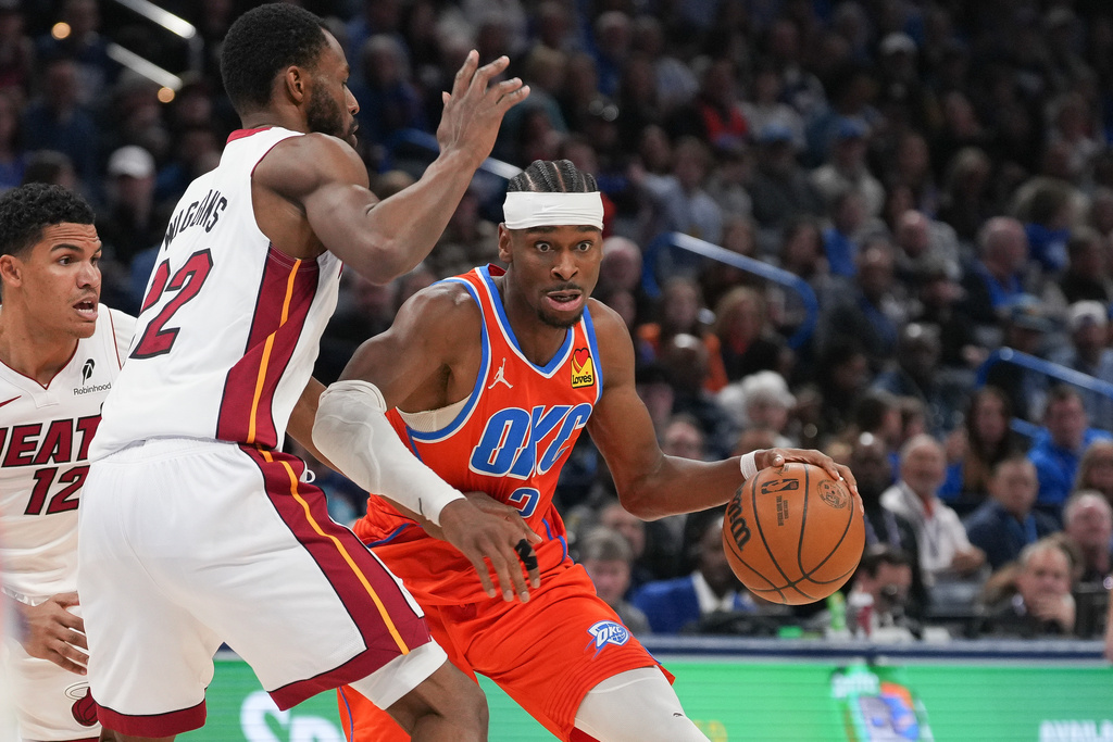 Oklahoma City Thunder guard Shai Gilgeous-Alexander, right, pushes past Miami Heat forward Andrew Wiggins during the second half of an NBA basketball game, Sunday, Jan. 11, 2026, in Oklahoma City. (AP Photo/Kyle Phillips)