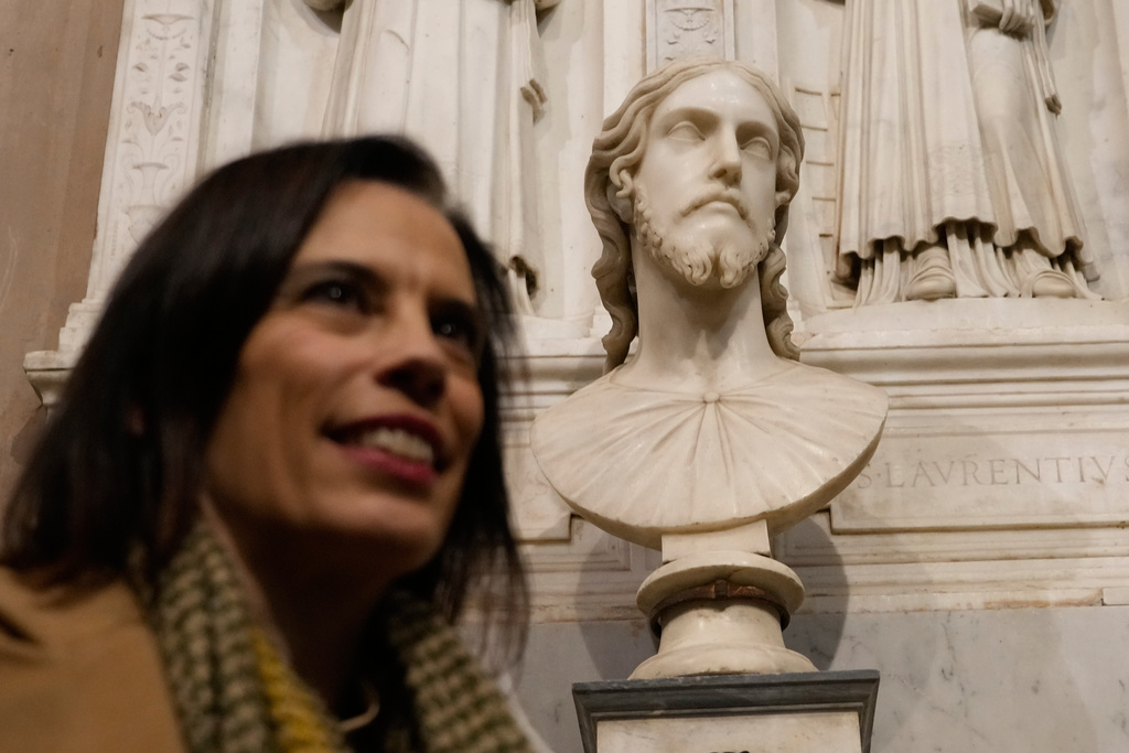 Italian researcher Valentina Salerno poses for photographers near the sculpted bust held inside the Basilica of Saint Agnes Outside the Walls, in Rome, Italy, Wednesday, March 4, 2026, which, in light of new studies, may be reattributed to Michelangelo Buonarroti. (AP Photo/Gregorio Borgia)