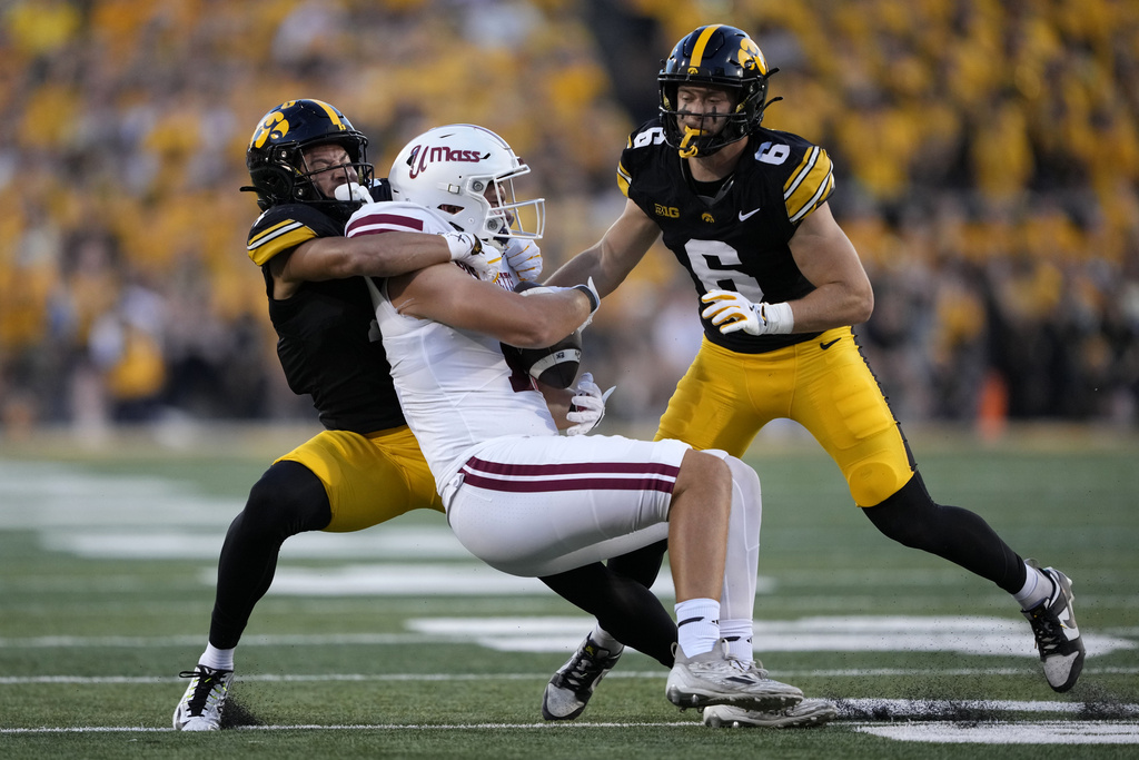 Massachusetts tight end Max Dowling, center, is tackled by Iowa defensive back Koen Entringer, left, and defensive back Zach Lutmer (6) after catching a pass during the first half of an NCAA college football game, Saturday, Sept. 13, 2025, in Iowa City, Iowa. (AP Photo/Charlie Neibergall)