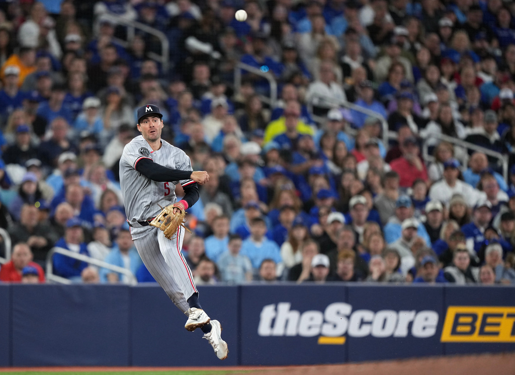Minnesota Twins third baseman Ryan Kreidler makes a leaping throw to put out Toronto Blue Jays designated hitter George Springer at first base during third-inning baseball game action in Toronto, Saturday, April 11, 2026. (Nathan Denette/The Canadian Press via AP)
