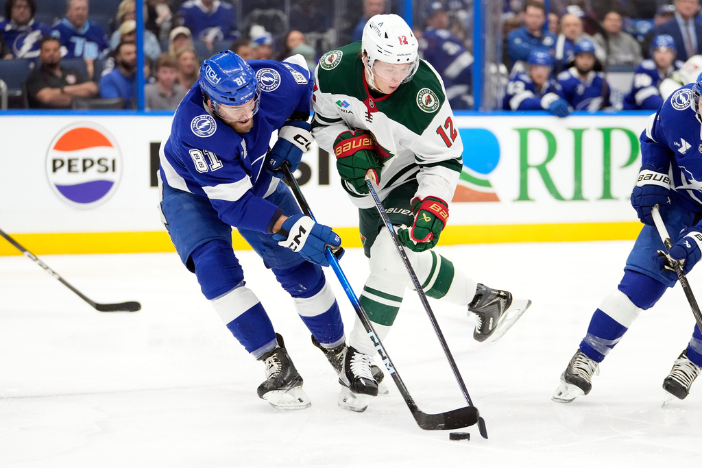 Tampa Bay Lightning defenseman Erik Cernak (81) and Minnesota Wild left wing Matt Boldy (12) battle for a loose puck during the first period of an NHL hockey game Tuesday, March 24, 2026, in Tampa, Fla. (AP Photo/Chris O'Meara)