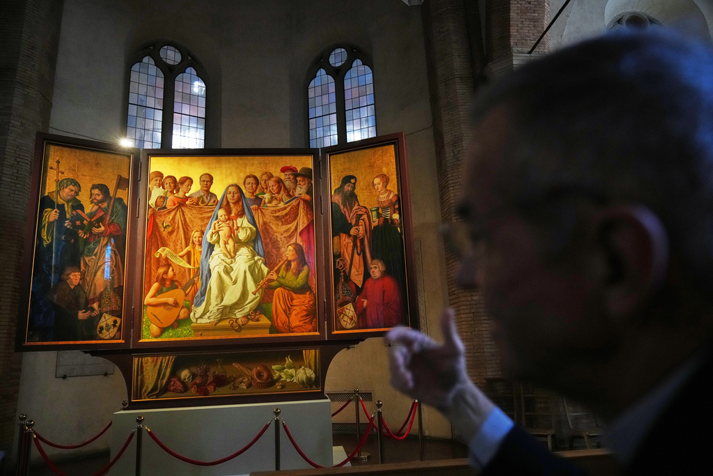 Mons. Peter Klasvogt, the rector of the Teutonic College, talks during an interview with the Associated Press next to a painting exposed in the chapel of the Teutonic College by German artist Michael Triegel, who portrayed as St. Peter Burkhard Scheffler, a homeless man who died from the cold in 2022 on the edge of St. Peter's Square, at the Vatican, Wednesday, Dec. 10, 2025. (AP Photo/Alessandra Tarantino)