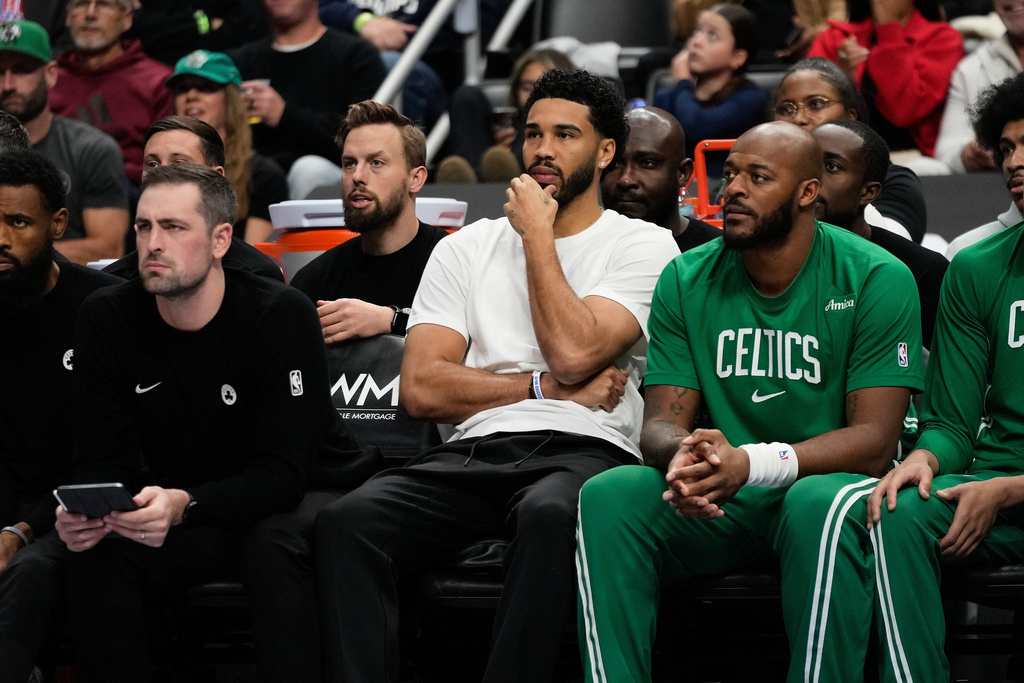 Boston Celtics forward Jayson Tatum, center, watches from the bench during the first half of an NBA basketball game against the Detroit Pistons, Sunday, Oct. 26, 2025, in Detroit. (AP Photo/Ryan Sun)