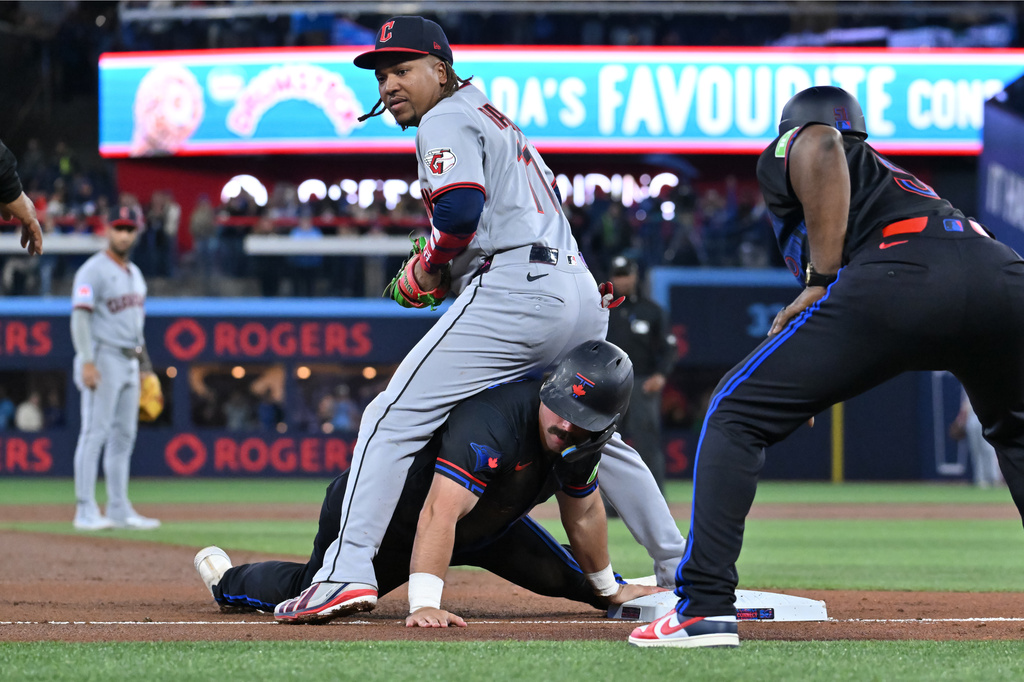 Toronto Blue Jays' Davis Schneider (bottom) slides safely into third base ahead of a tag by Cleveland Guardians third baseman Jose Ramirez (11) in first inning of a baseball game in Toronto on Friday, April 24, 2026. (Jon Blacker/The Canadian Press via AP)