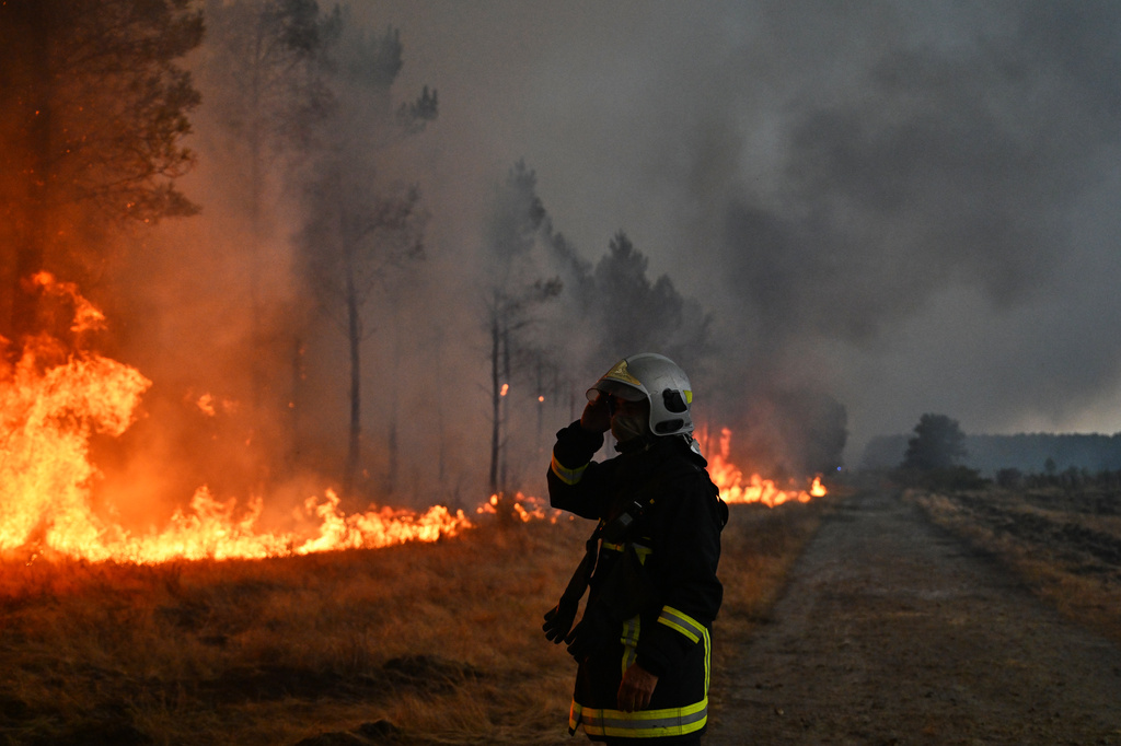 A firefighter gestures next to burning trees as a wildfire rages near Marcheprime, outside, Bordeaux, France, Sunday, July 26, 2026. (AP Photo/Emma Da Silva)
