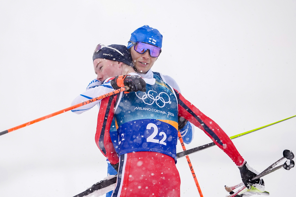 Silver medalist Eero Hirvonen, of Finland, right, embraces gold medalist Jens Luraas Oftebro, of Norway, after crossing the finish line in the nordic combined team sprint at the 2026 Winter Olympics, in Tesero, Italy, Thursday, Feb. 19, 2026. (AP Photo/Matthias Schrader)