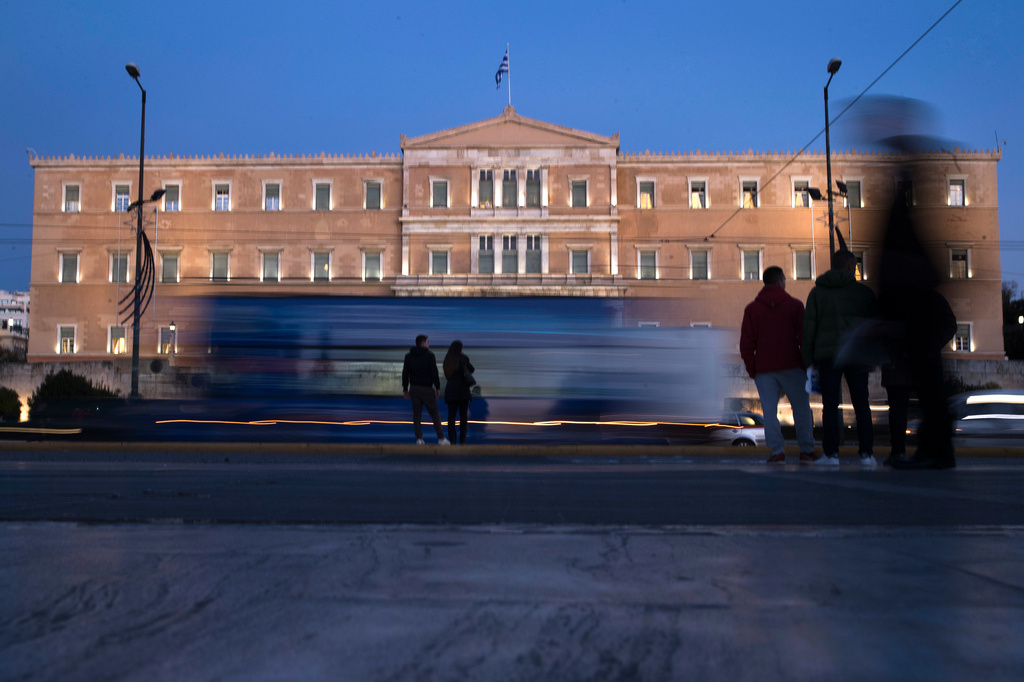 FILE - People stand in front of the Greek Parliament as vehicles drive past in central Athens, on Nov. 21, 2017. (AP Photo/Petros Giannakouris, File)