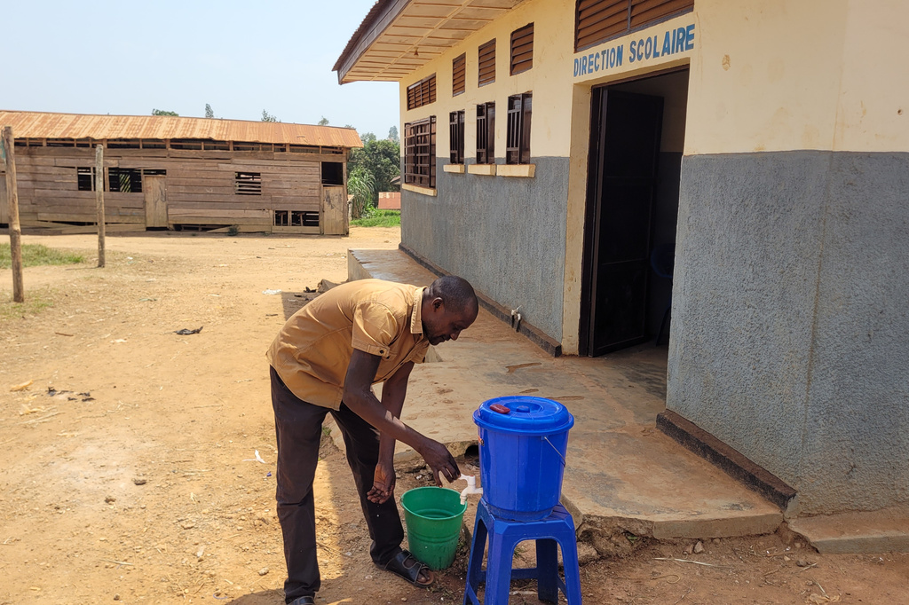 A parent who came for his child's school resumption washes his hands outside a school in Ituri province, eastern Congo, Thursday, Aug. 27, 2026. (AP Photo/Constant Same Bagalwa)