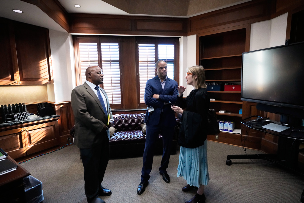 Calvin Duncan, left, an exoneree who was elected Orleans Parish clerk of criminal court, talks in his office with outgoing clerk Darren Lombard, center, and legal advisor Emily Rattner, on the first day of his term, Monday, May 4, 2026, in New Orleans. (AP Photo/Gerald Herbert)