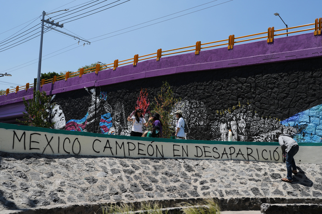 A person protesting the more than the 134,000 disappeared people, writes in spray paint, "Mexico, champion of disappearances" as Mexico prepares to host the 2026 FIFA World Cup in Mexico City, Saturday, May 30, 2026. (AP Photo/Marco Ugarte)
