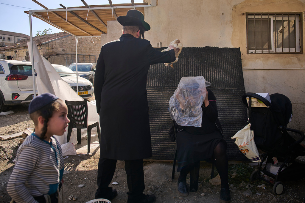 An ultra-Orthodox Jewish man swings a chicken over a woman head in Jerusalem, Monday, Sept. 29, 2025, as part of the Kaparot ritual before the Jewish holiday of Yom Kippur. (AP Photo/Ohad Zwigenberg)