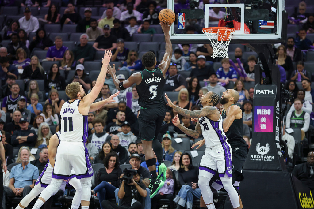 Minnesota Timberwolves guard Anthony Edwards (5) makes a floating jump shot with Sacramento Kings center Domantas Sabonis (11) and guard Demar Derozan (10) defending during the first half of an NBA basketball game Sunday, Nov. 9, 2025, in Sacramento, Calif. (AP Photo/Sara Nevis)