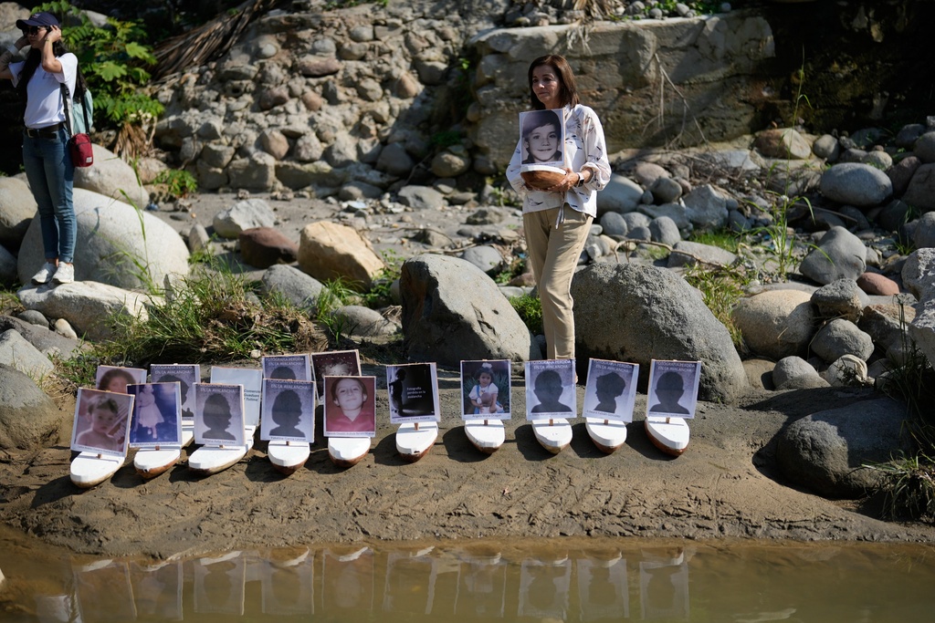 Martha Lucia Lopez holds a boat with a photo of her son Sergio Melendro Lopez missing since the Nevado del Ruiz eruption before the release of small boats with photos of the missing children, into the Guali River in Honda, Colombia, Wednesday, Nov. 12, 2025, on the eve of the 40th anniversary of the disaster that killed about 25,000 people. (AP Photo/Fernando Vergara)