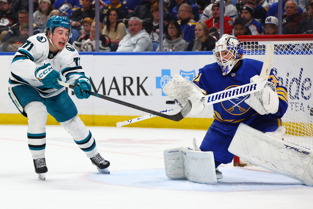 Buffalo Sabres goaltender Alex Lyon, right, stops a tipped shot by San Jose Sharks center Macklin Celebrini (71) during the second period of an NHL hockey game, Tuesday, March 10, 2026, in Buffalo, N.Y. (AP Photo/Jeffrey T. Barnes)