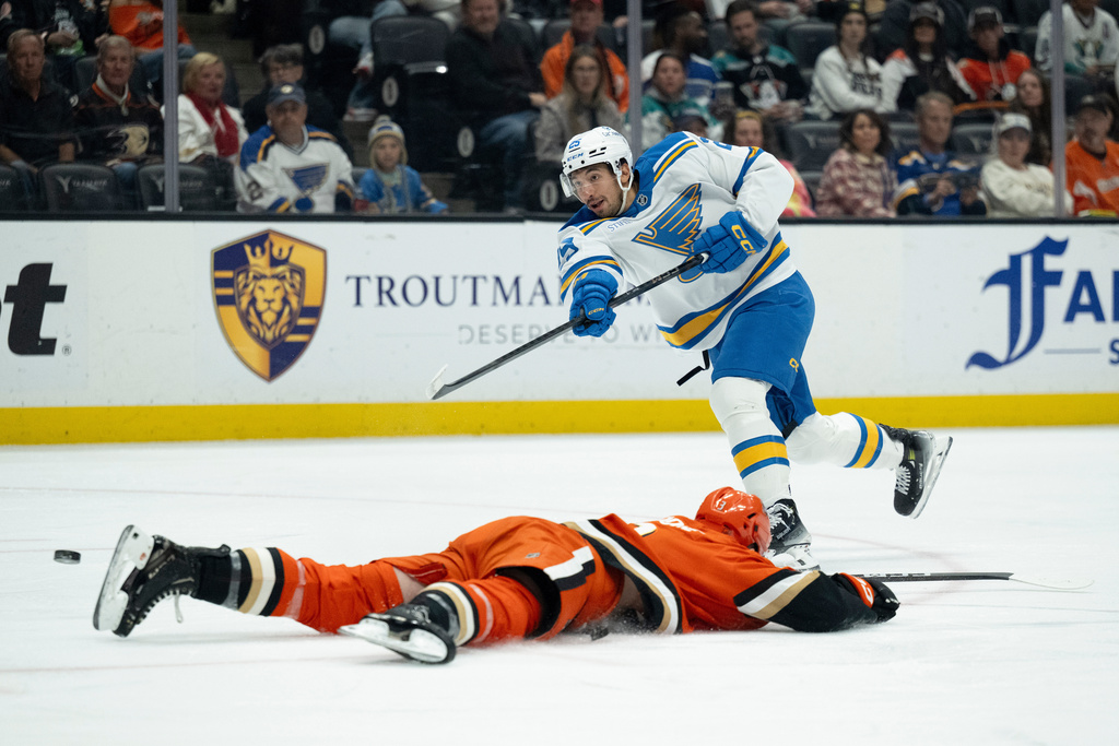 St. Louis Blues right wing Jordan Kyrou, top, shoots to score past the slide by Anaheim Ducks defenseman Ian Moore during the second period of an NHL hockey game, Sunday, March 8, 2026, in Anaheim, Calif. (AP Photo/Kyusung Gong)