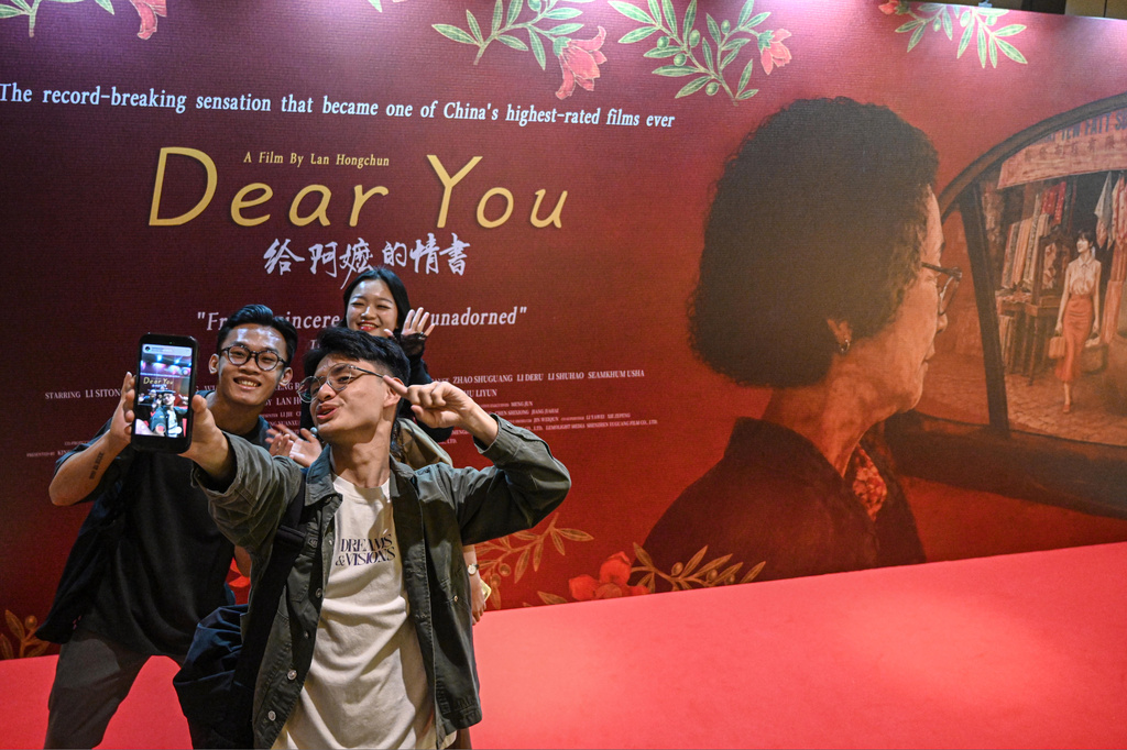 In this photo released by Xinhua News Agency, viewers take selfie in front of an advertisement for the Chinese film "Dear You" during its premiere in Jakarta, Indonesia, on Aug. 5, 2026. (Agung Kuncahya B./Xinhua via AP)