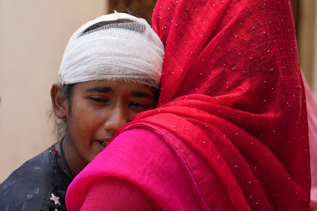 Shweta Yadav, 16, who was injured while trying to save her brother Summit Yadav, 24, after a wall of their neighbor's house collapsed following dust storms and heavy rain, is consoled by a relative in Prayagraj, India, Thursday, May 14, 2026. (AP Photo/Rajesh Kumar Singh)