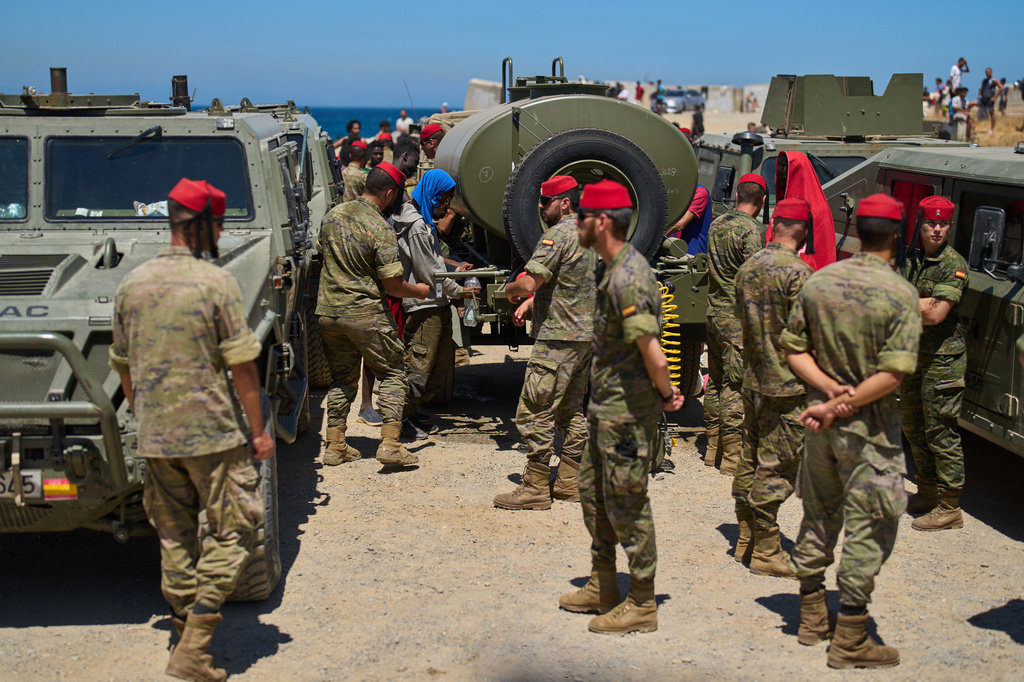 Migrants who crossed into Spain from Morocco collect water distributed by Spanish soldiers in the Spanish enclave of Ceuta, Sunday, Aug. 2, 2026. (AP Photo/Bernat Armangue)