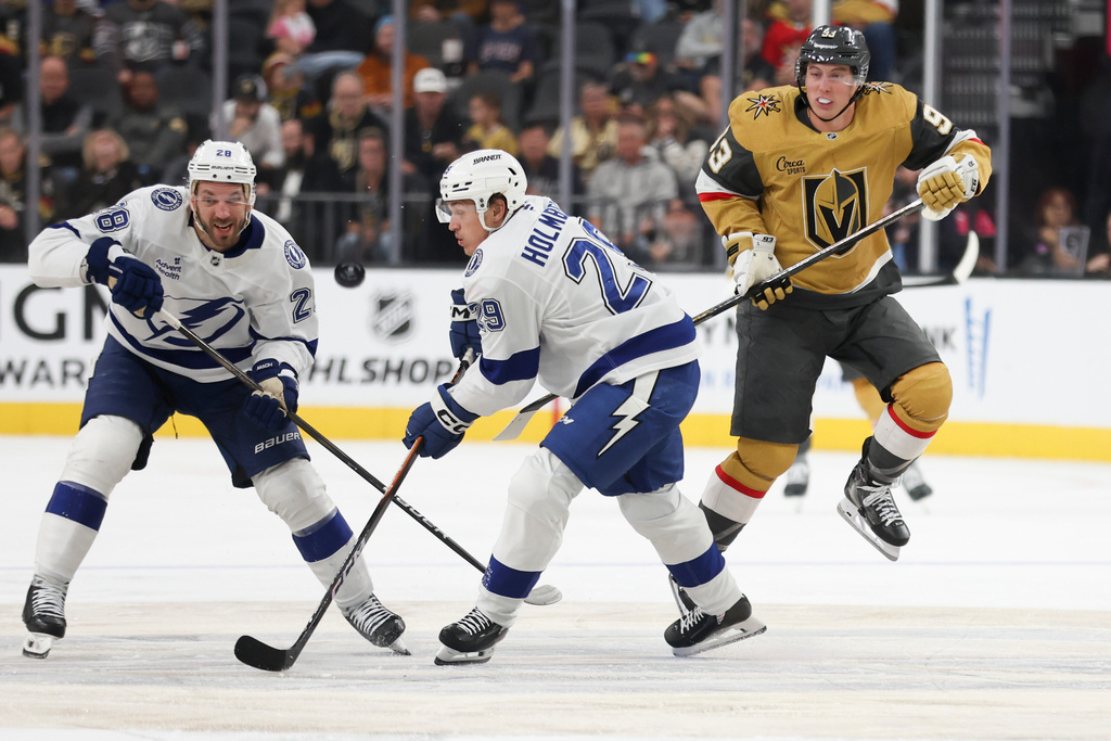 Tampa Bay Lightning center Zemgus Girgensons (28), Lightning right wing Pontus Holmberg (29) and Vegas Golden Knights right wing Mitch Marner (93) chase the puck during the second period of an NHL hockey game Thursday, Nov. 6, 2025, in Las Vegas. (AP Photo/Ian Maule)