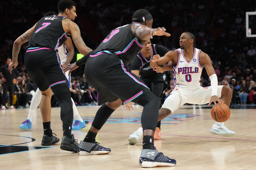 Miami Heat center Kel'el Ware (7) and center Bam Adebayo (13) defend Philadelphia 76ers guard Tyrese Maxey (0) during the first half of an NBA basketball game, Monday, March 30, 2026, in Miami. (AP Photo/Lynne Sladky)