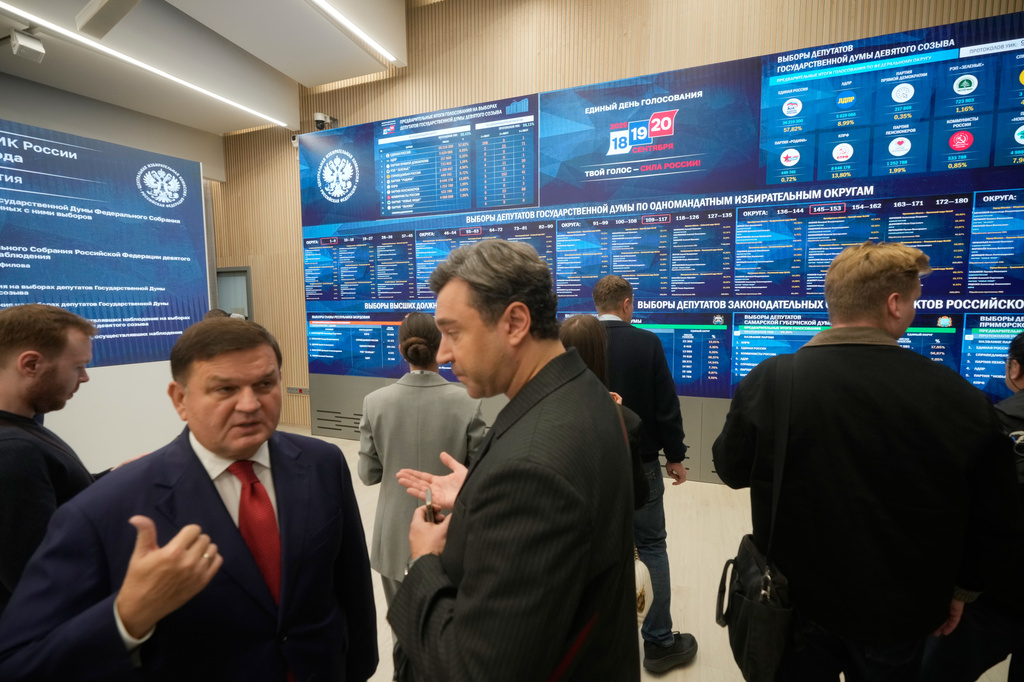 People stand next to video screens sowing preliminary voting results for Russian parliamentary elections at Russia's Central Election Committee headquarters, in Moscow, Russia, Monday, Sept. 21, 2026. (AP Photo/Pavel Bednyakov)