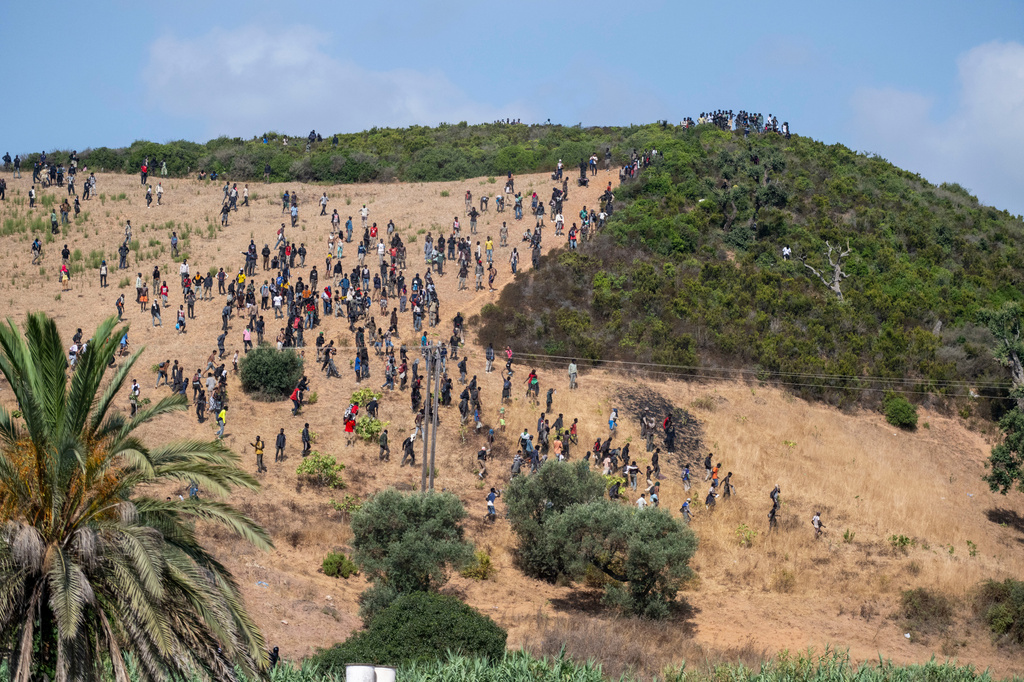 Migrants gather on a hill as they attempt crossing from the border town of Fnideq to the Spanish enclave of Ceuta, Saturday, Aug. 15, 2026. (AP Photo)