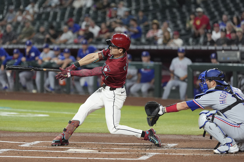 Arizona Diamondbacks' Corbin Carroll connects for a double as Texas Rangers catcher Kyle Higashioka, right, reaches for the ball during the first inning of a baseball game Wednesday, Sept. 3, 2025, in Phoenix. (AP Photo/Ross D. Franklin)