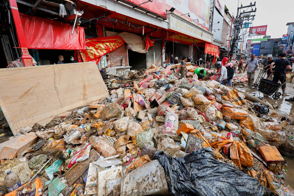 Peoples walk near goods damaged from floods in Songkhla province, southern Thailand, Saturday, Nov. 29, 2025. (AP Photo/Sarot Meksophawannakul)