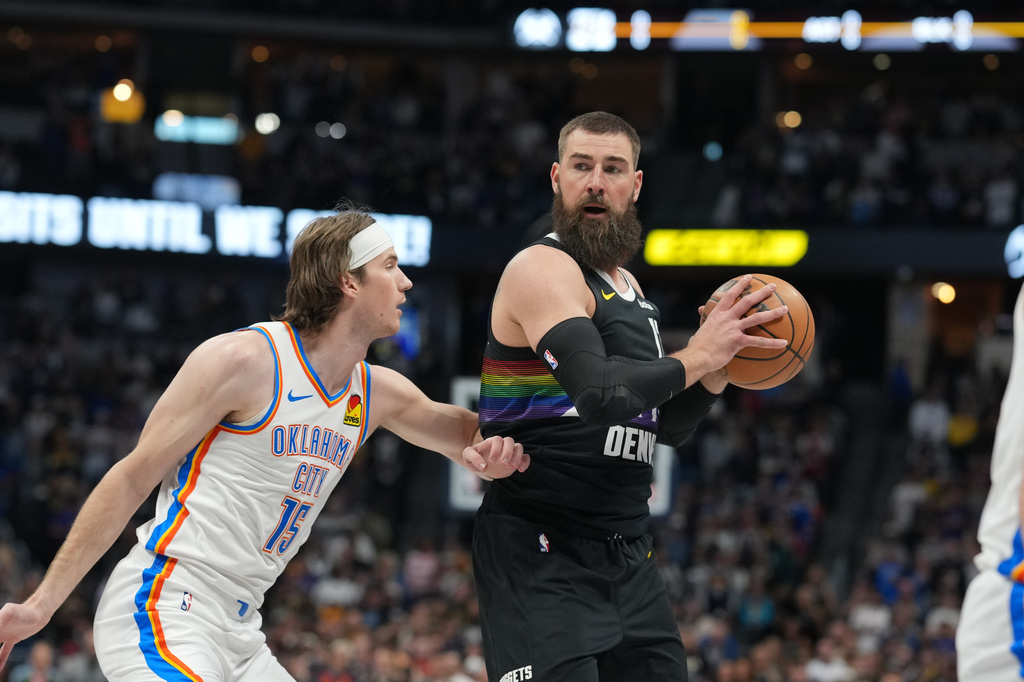 Denver Nuggets center Jonas Valančiūnas, right, looks to pass the ball as Oklahoma City Thunder center Branden Carlson defends in the first half of an NBA basketball game Friday, April 10, 2026, in Denver. (AP Photo/David Zalubowski)