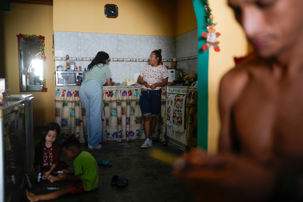 Mariela Gómez, a Venezuelan migrant who abandoned her journey with her children to the United States following President Donald Trump's immigration crackdown, chats with a relative while cooking Christmas dinner in Maracay, Venezuela, Friday, Dec. 24, 2025. (AP Photo/Matias Delacroix)