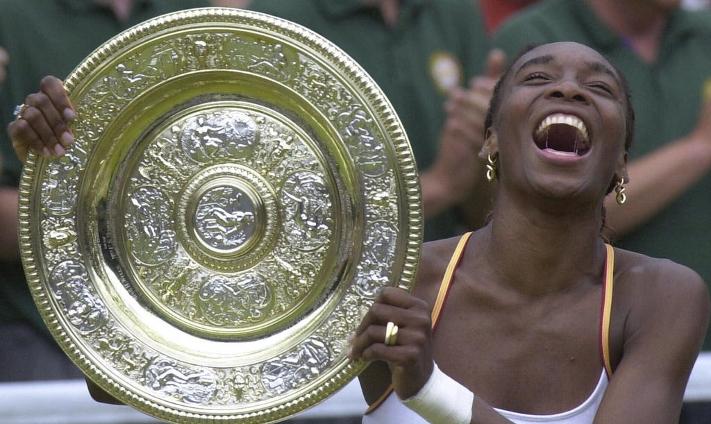 FILE - Venus Williams laughs as she holds the Women's Singles trophy on the Centre Court at Wimbledon Saturday, July 8, 2000. (AP Photo/Adam Butler, file)