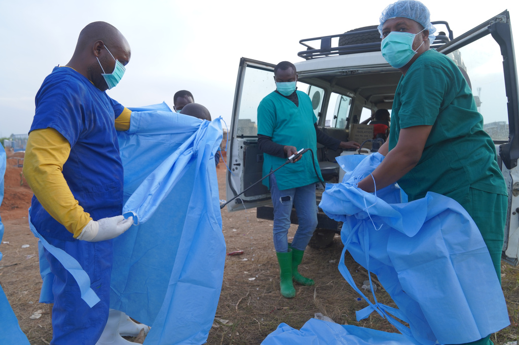 A health worker sprays a colleague with disinfectant after taking part in a burial service for 3-year-old Mave Mercienne, who died of Ebola, in Bunia, Ituri province, eastern Congo, Tuesday, Aug. 18, 2026. (AP Photo/Dieudonne Dirole)