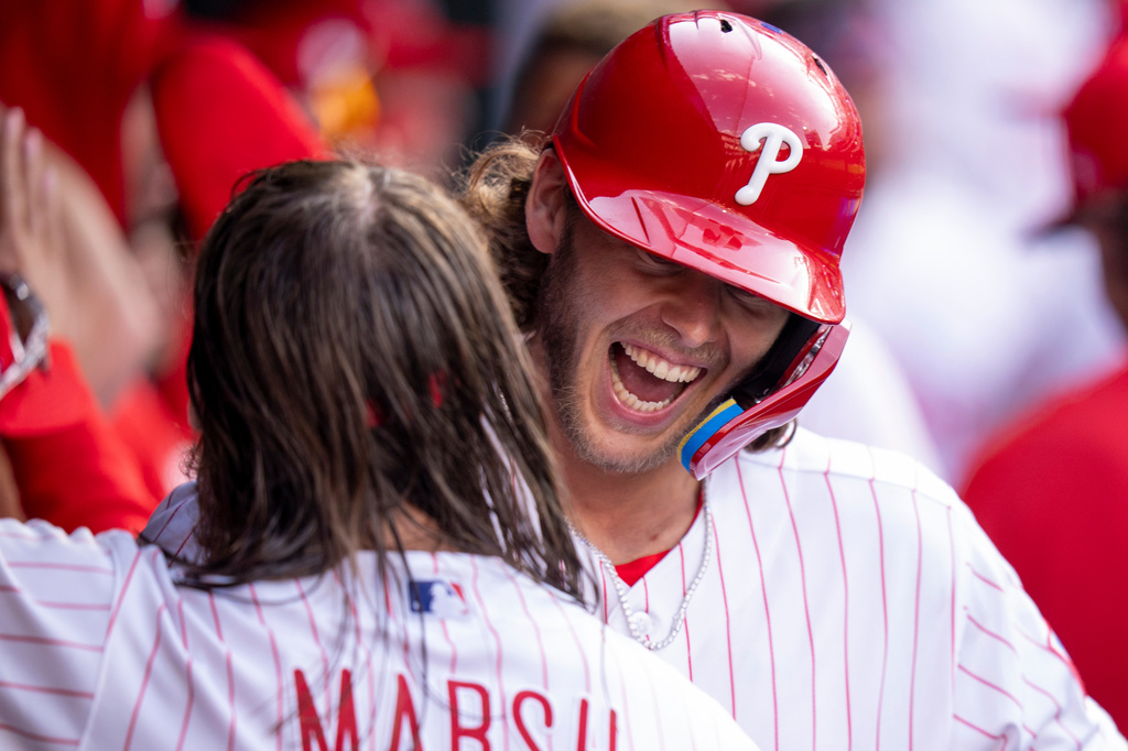 Philadelphia Phillies' Alec Bohm, right, celebrates his three-run home run with Brandon Marsh, left, during the fifth inning of an opening-day baseball game against the Texas Rangers, Thursday, March 26, 2026, in Philadelphia. (AP Photo/Chris Szagola)