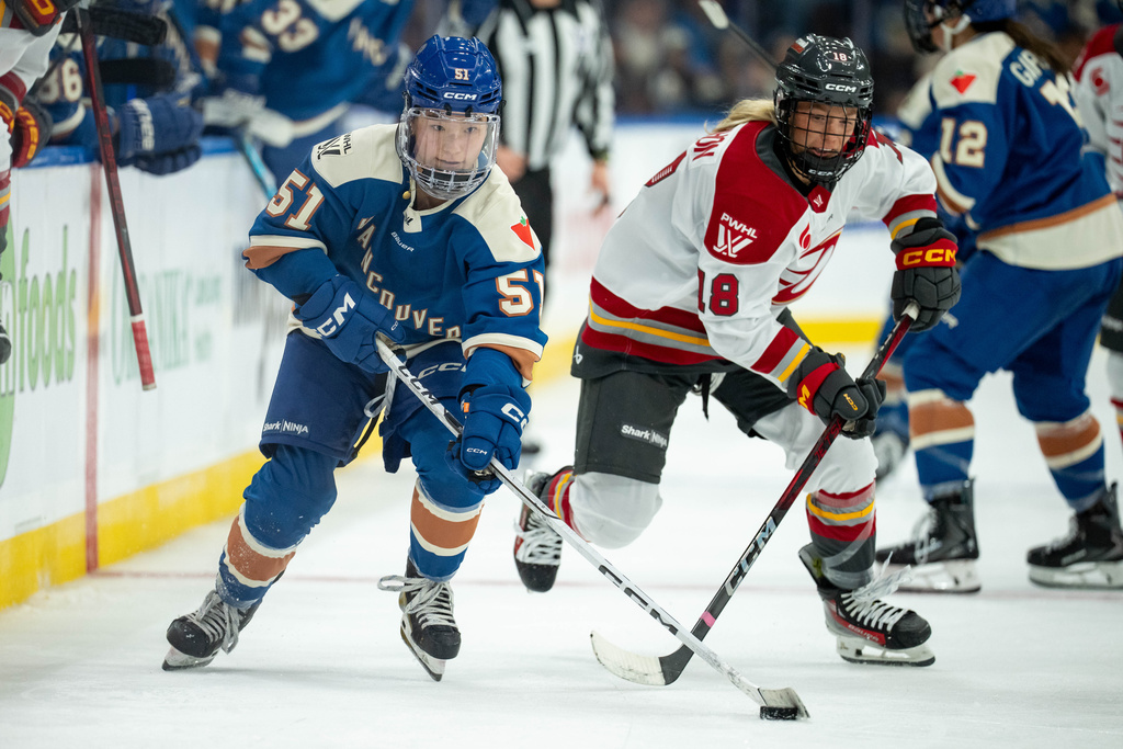 Vancouver Goldeneyes' Anna Segedi (51) and Ottawa Charge's Mannon McMahon (18) vie for the puck during the third period of a PWHL hockey game in Vancouver, British Columbia, Tuesday, Dec. 16, 2025. (Ethan Cairns/The Canadian Press via AP)