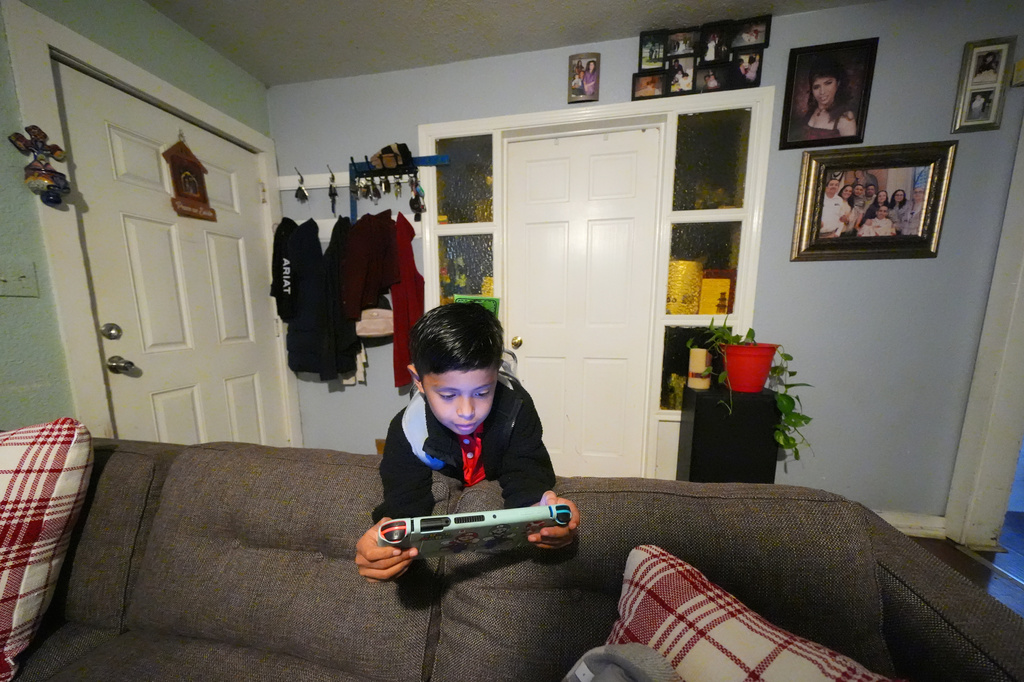 Ian Contreras plays on a gaming device while waiting for his mother to take him to school Thursday, April 9, 2026, in Fort Worth, Texas. (AP Photo/Julio Cortez)