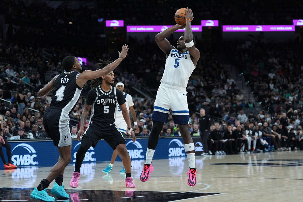 Minnesota Timberwolves guard Anthony Edwards (5) shoots over San Antonio Spurs guard De'aaron Fox (4) and guard Stephon Castle (5) during the first half of an NBA basketball game in San Antonio, Saturday, Jan. 17, 2026. (AP Photo/Eric Gay)