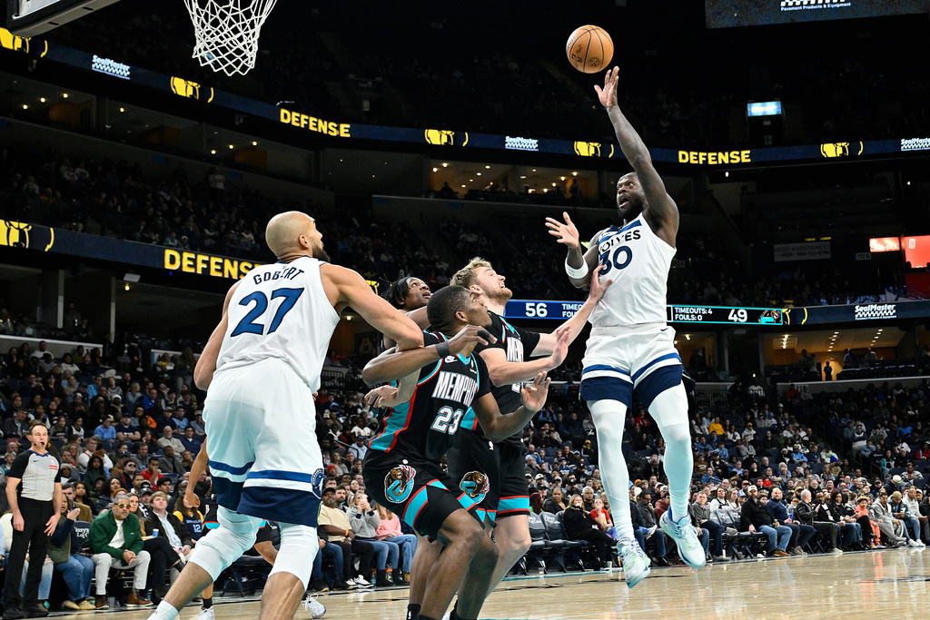 Minnesota Timberwolves forward Julius Randle (30) shoots over Memphis Grizzlies forward Cedric Coward (23), guard Cam Spencer, second from right, and forward GG Jackson II, fourth from right, as Timberwolves center Rudy Gobert (27) moves for position in the first half of an NBA basketball game Saturday, Jan. 31, 2026, in Memphis, Tenn. (AP Photo/Brandon Dill)