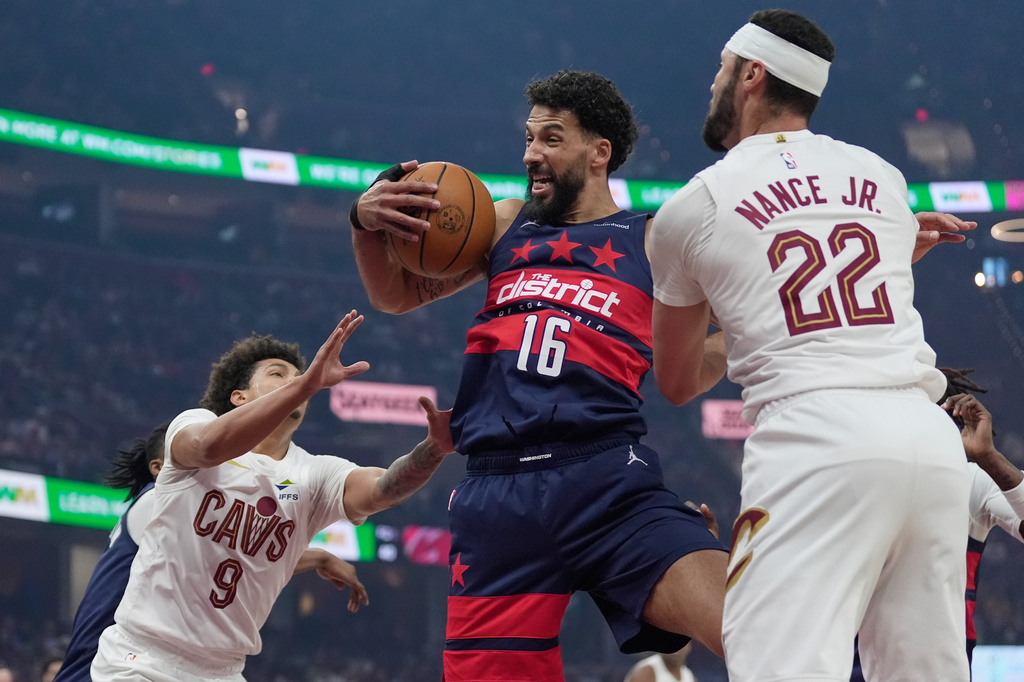 Washington Wizards forward Anthony Gill (16) grabs a rebound between Cleveland Cavaliers guard Craig Porter Jr. (9) and forward Larry Nance Jr. (22) in the first half of an NBA basketball game in Cleveland, Sunday, April 12, 2026. (AP Photo/Sue Ogrocki)