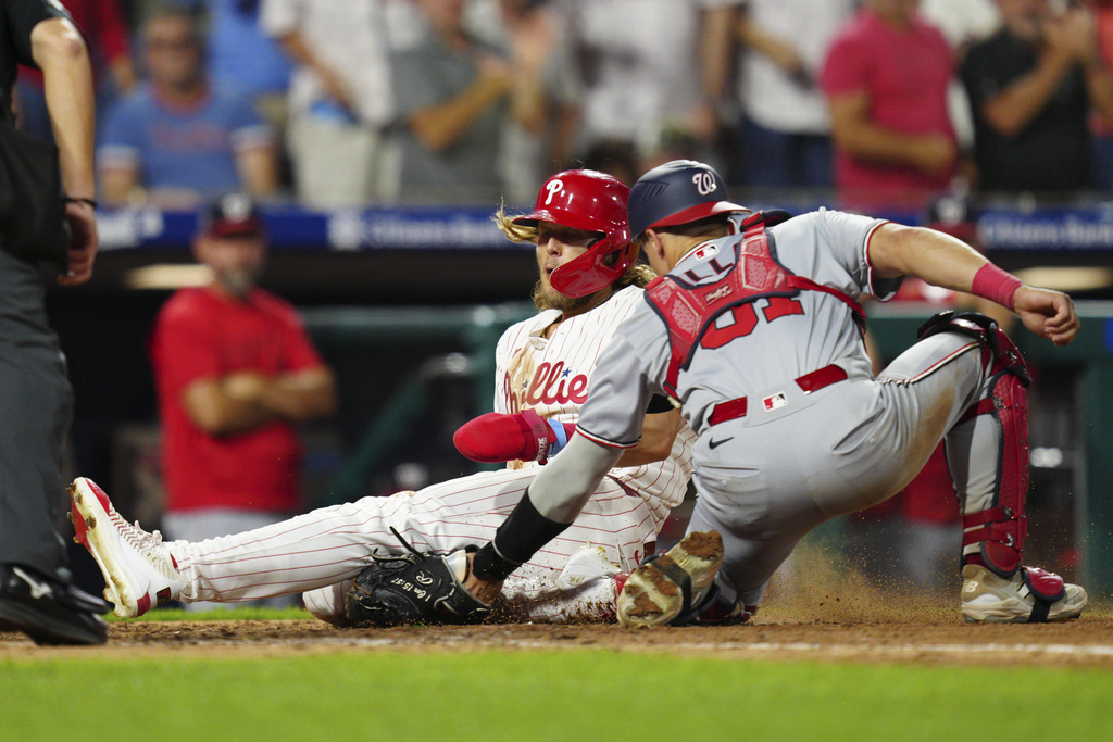 Philadelphia Phillies' Alec Bohm, left, is tagged out at home plate by Washington Nationals' Drew Millas (81) during the eighth inning of a baseball game, Saturday, Aug. 23, 2025, in Philadelphia. (AP Photo/Derik Hamilton)