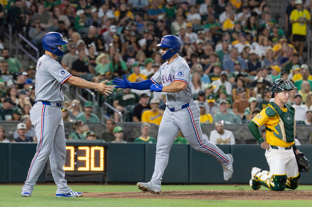 Texas Rangers' Wyatt Langford, right, high-fives Corey Seager after hitting a two-run home run during the sixth inning of a baseball game against the Athletics Saturday, Aug. 15, 2026, in West Sacramento, Calif. (AP Photo/Sara Nevis)