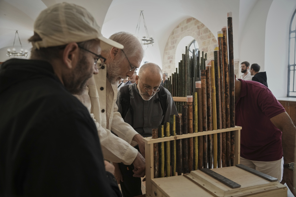 People look at an 11th-century organ that researchers say is the oldest in the Christian world was played for the first time in 800 years after restoration, in Saint Savior's Monastery of Jerusalem's Old City, Tuesday, Sept. 9, 2025. (AP Photo/Mahmoud Illean)