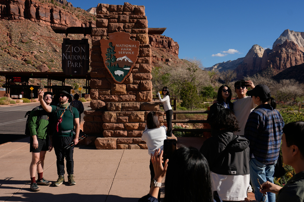 People stand near an entrance to Zion National Park, Wednesday, Oct. 1, 2025, in Springdale, Utah. (AP Photo/John Locher)