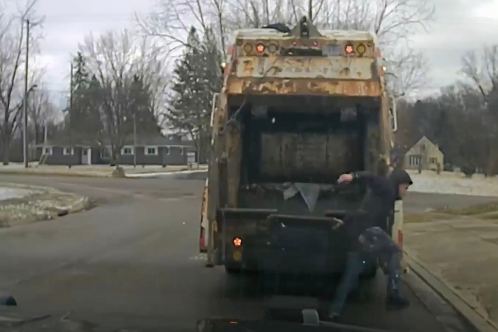 This image made from video provided by a Huber Heights police officer's dash camera shows a suspect jumping out of a garage can and fleeing from police on Monday, Feb. 23, 2026, in Huber Heights, Ohio. (Huber Heights Police Department via AP)