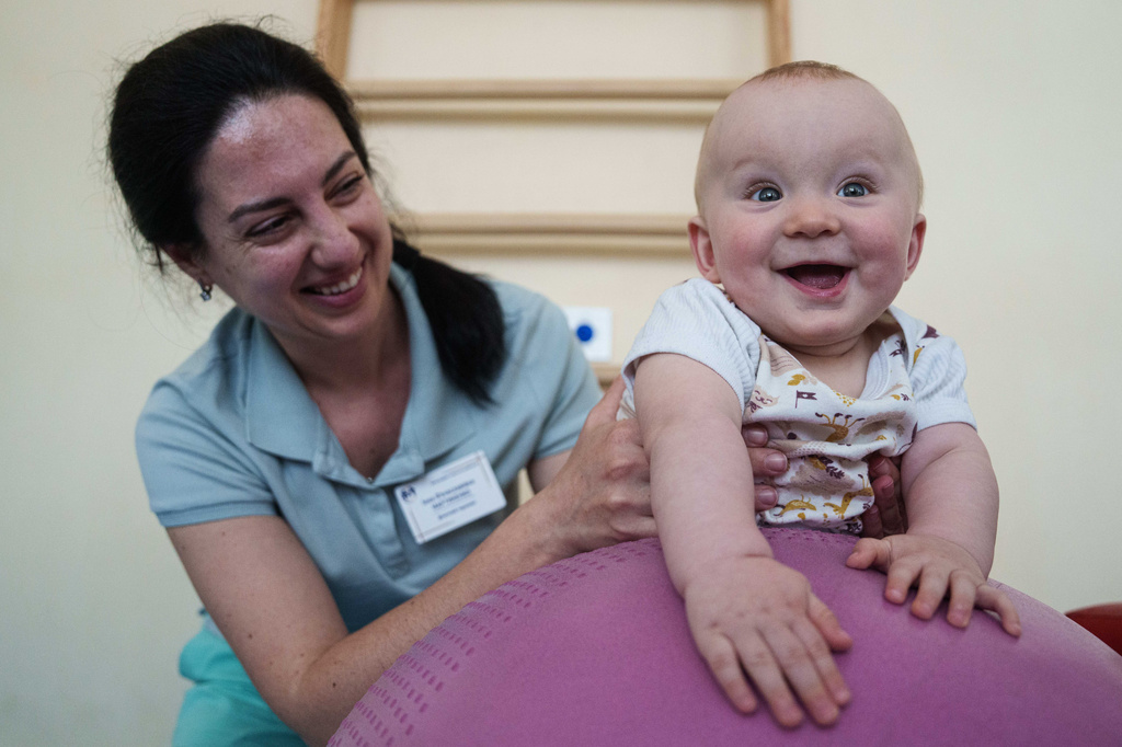 A medic does exercises with a 1-year-old child during a therapy session at the children's regional hospital in Zaporizhzhia, Ukraine, Thursday, May 7, 2026. (AP Photo/Evgeniy Maloletka)
