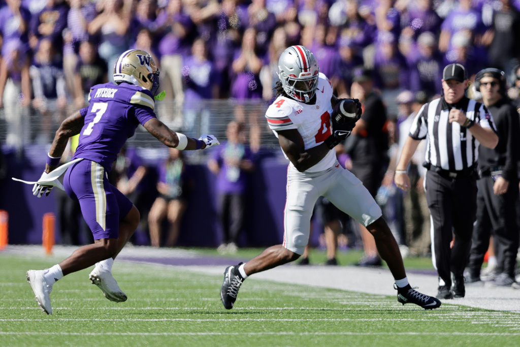 Ohio State wide receiver Jeremiah Smith (4) catches a pass with Washington cornerback Ephesians Prysock (7) defending during the first half of an NCAA college football game, Saturday, Sept. 27, 2025, in Seattle. (AP Photo/John Froschauer)