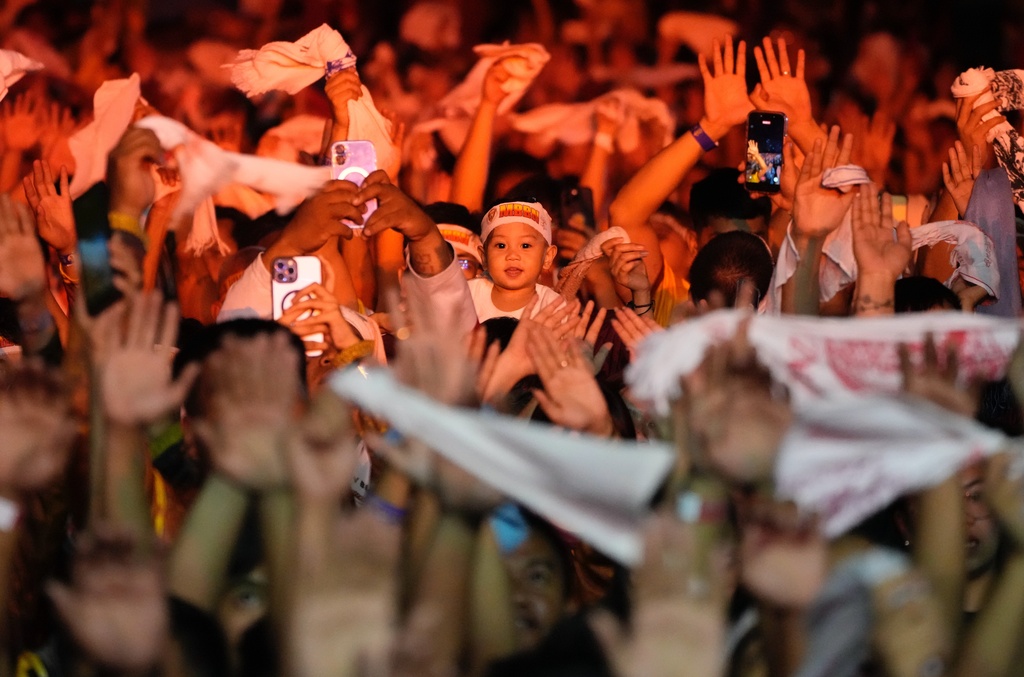 Catholic devotees raise their hands and wave white towels as a carriage carrying the image of Jesus Nazareno passes by during its annual procession in Manila, Philippines, on its feast day Friday Jan. 9, 2026. (AP Photo/Aaron Favila)