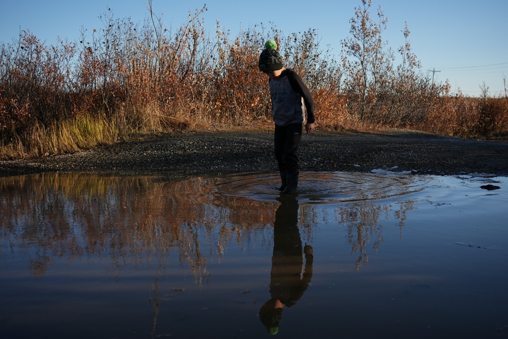 James Schaeffer, 7, plays on a road where thawing permafrost has caused the ground to warp in Kotzebue, Alaska, Friday, Sept. 26, 2025. (AP Photo/Annika Hammerschlag)