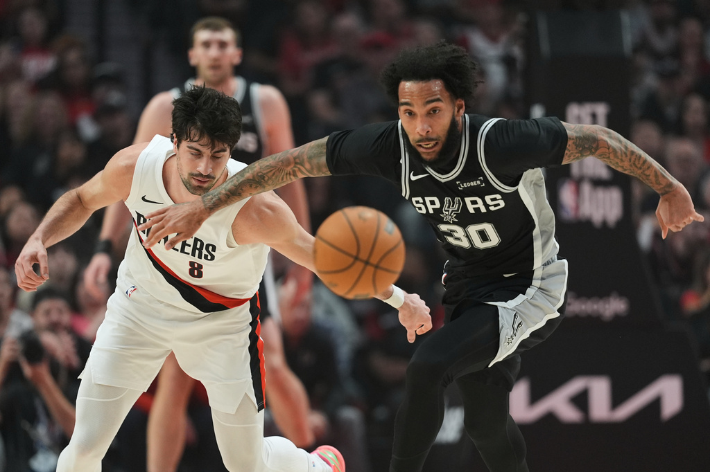 Portland Trail Blazers forward Deni Avdija (8) and San Antonio Spurs forward Julian Champagnie (30) chase a loose ball during the first half in Game 3 of a first-round NBA playoffs basketball series in Portland, Ore, Friday, April 24, 2026. (AP Photo/Jenny Kane)
