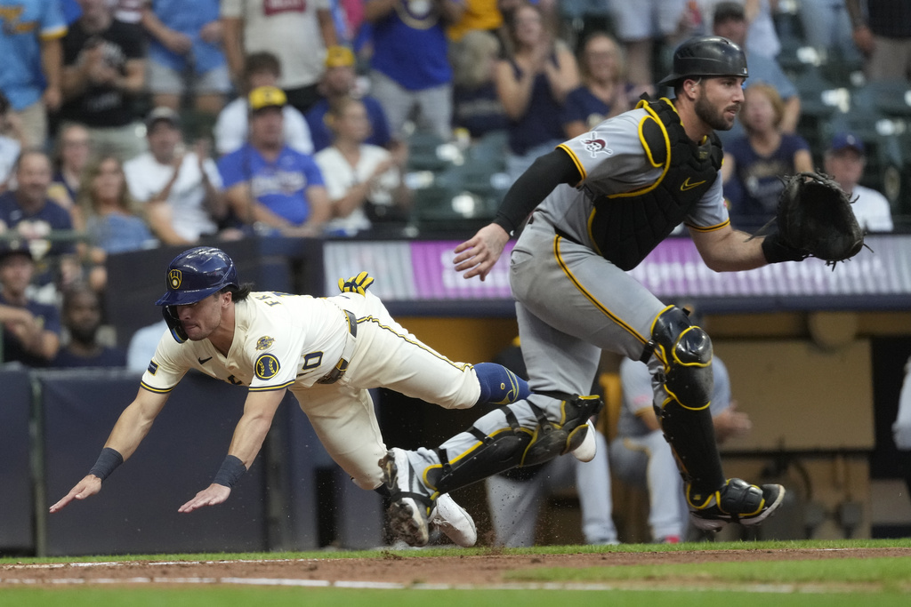 Milwaukee Brewers' Sal Frelick, left, slides at home to score a run past Pittsburgh Pirates' Joey Bart during the third inning of a baseball game, Monday, Aug. 11, 2025, in Milwaukee. (AP Photo/Aaron Gash)